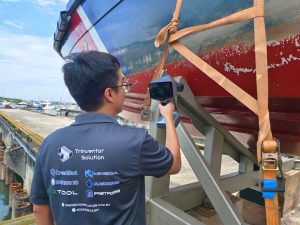 Handheld 3D scanner measuring a boat hull on a cradle at a boatyard