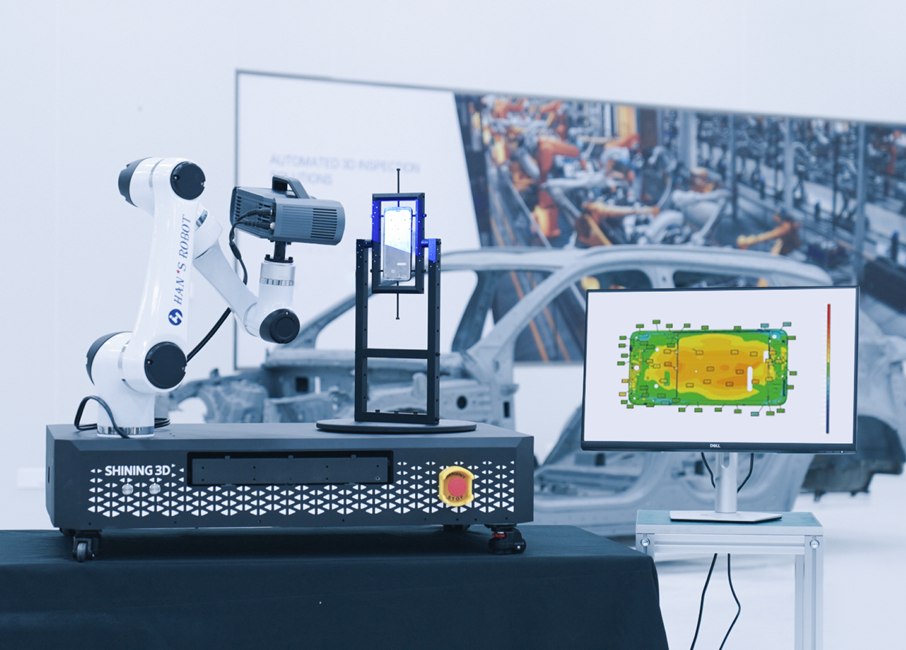 Structured-light 3D scanner mounted on a robot arm inspecting a part on a turntable, with a deviation map on screen