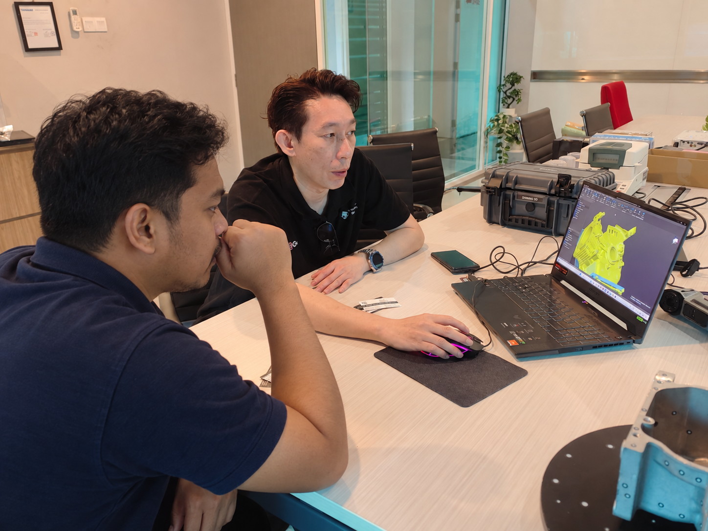 Consultant and customer reviewing a 3D scan on a laptop with a Shining 3D case open on the table