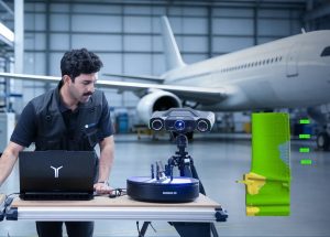 Engineer beside a scanned aerospace component and its CAD deviation map with tolerance callouts on screen