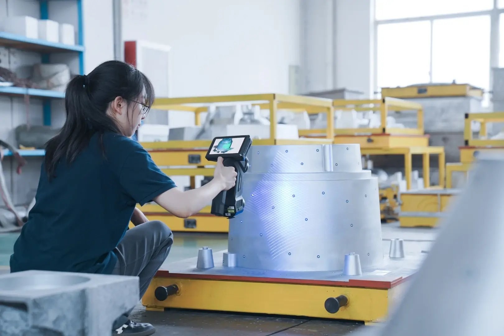 Handheld 3D scanner capturing a large machined component in a workshop