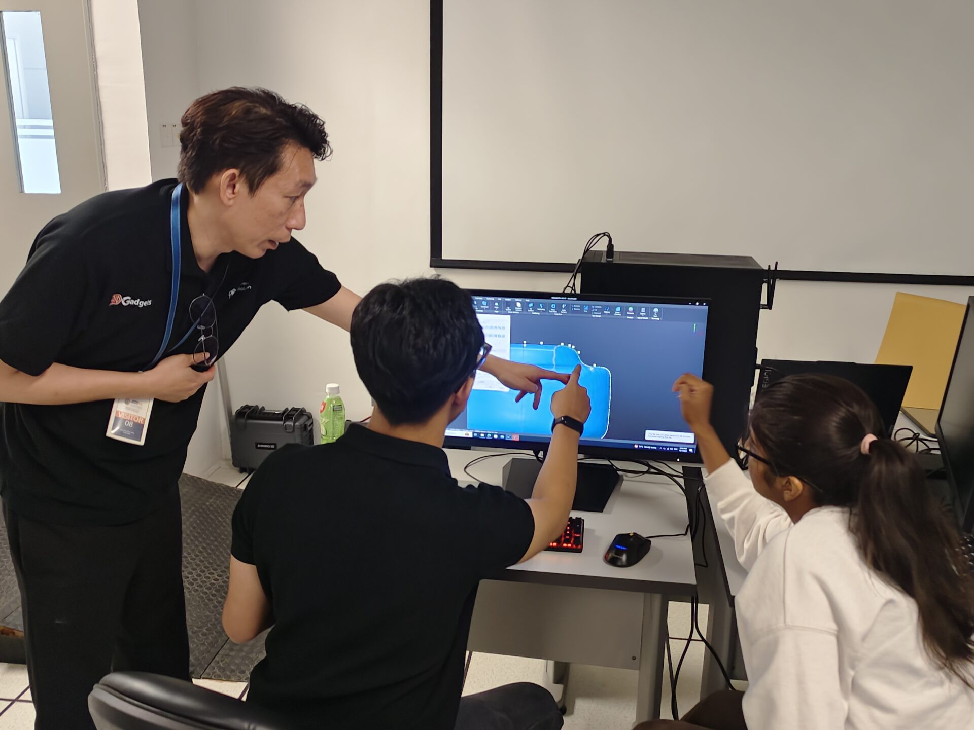 Trainer pointing at a CAD screen while two people follow along in an office