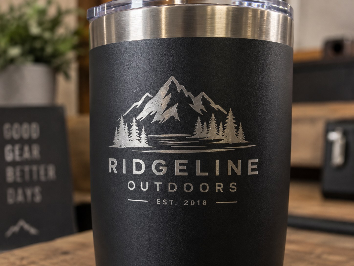 Close-up of a matte black tumbler with a mountain logo engraved through the coating to the stainless beneath