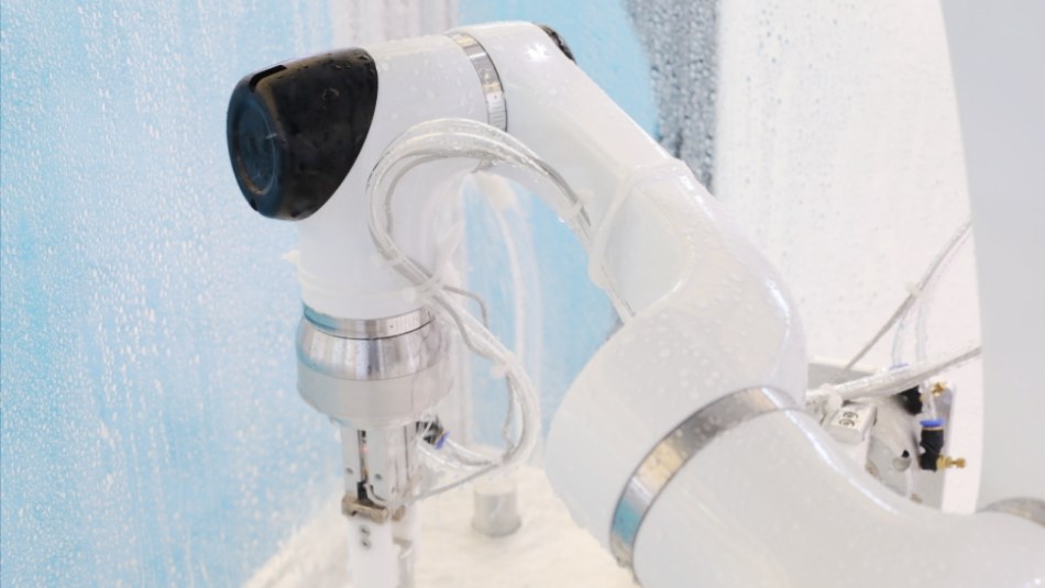 Collaborative robot gripper holding a part in a wet production cell