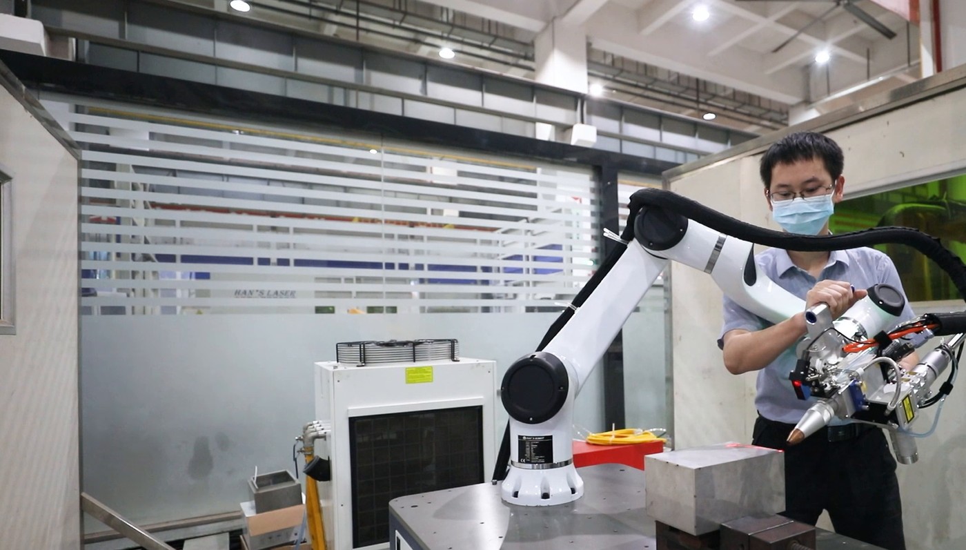 Operator hand-guiding a Huayan collaborative robot with a laser welding head