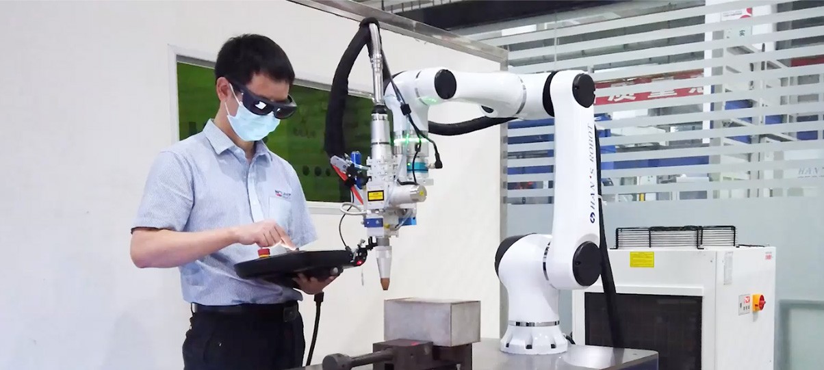 Operator teaching a Huayan cobot at a laser welding workstation