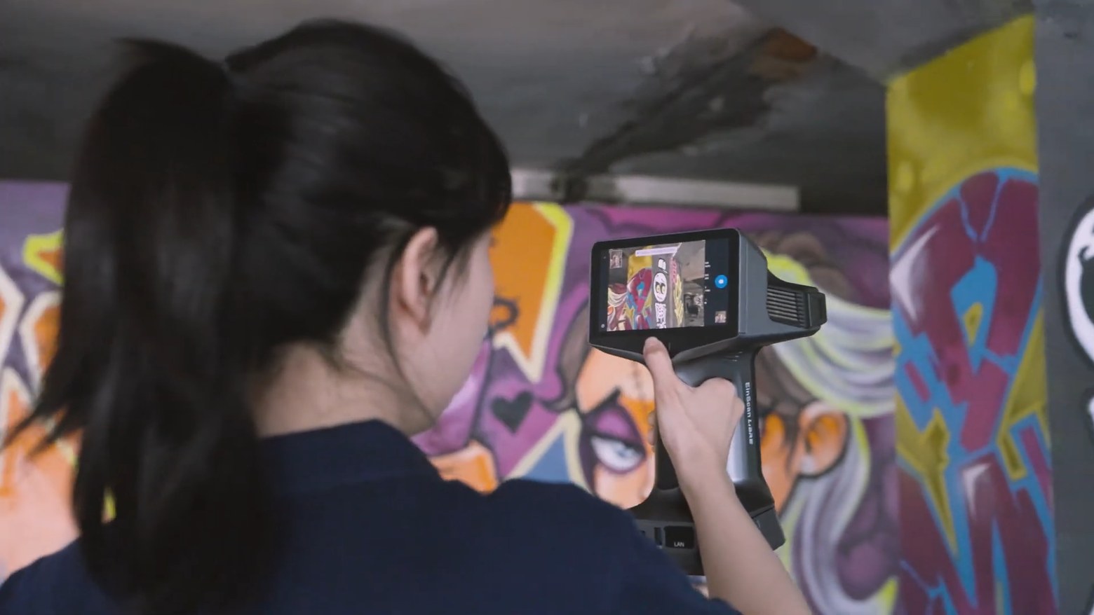A Shining 3D EinScan Libre scanner being used to capture a painted mural, with the colour image visible on the scanner screen