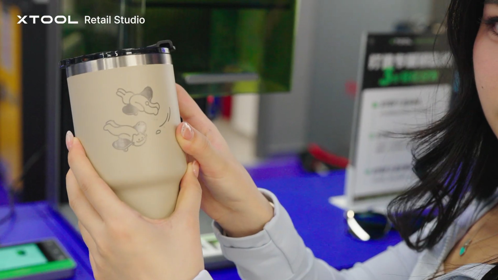A customer holding a personalised insulated tumbler engraved with a cartoon motif at a retail counter