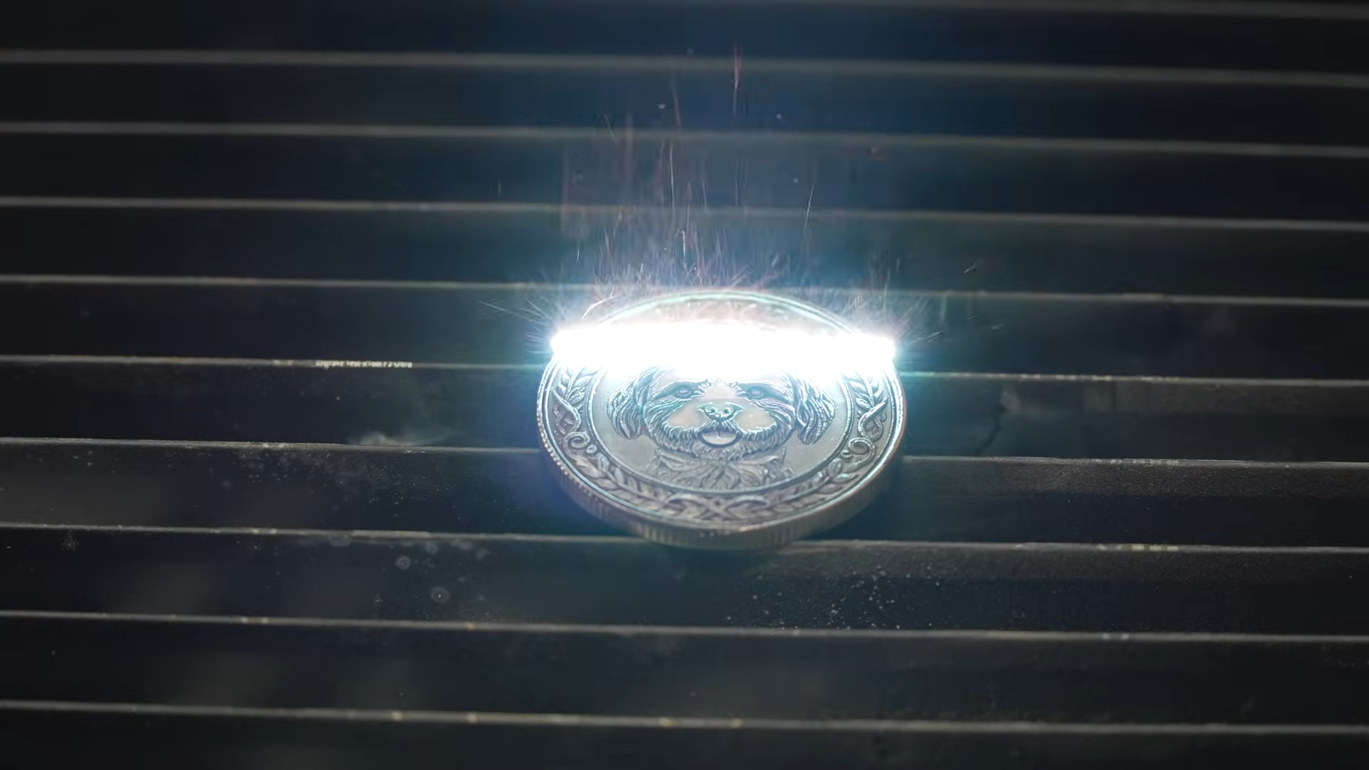 Fiber laser engraving a steel coin with a dog portrait, sparks coming off the metal