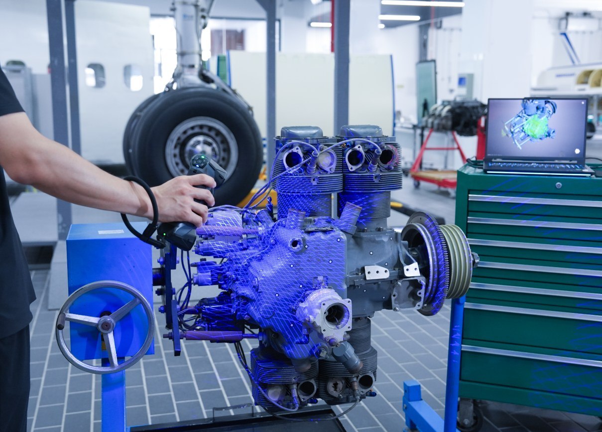 Engine assembly inspected in a workshop with scan data open on a laptop