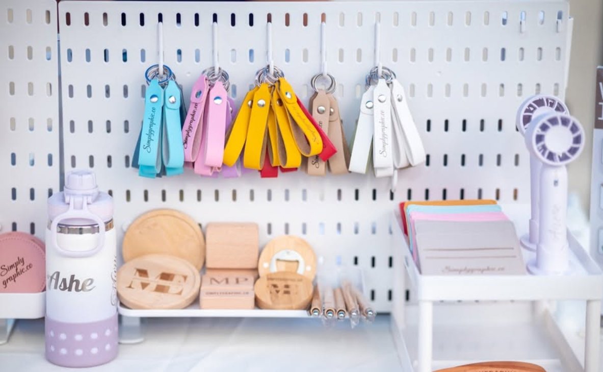 Laser-engraved products on display: leather keychains, wooden coasters, pens and a personalised tumbler