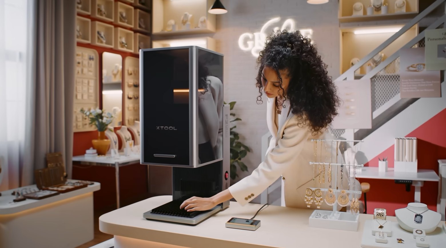 A jeweller operating an xTool fiber laser at a boutique counter to personalise metal jewellery