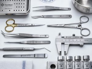 Marked surgical and laboratory instruments laid out flat, each carrying a serial number and a data matrix code
