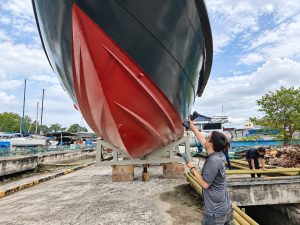 Engineer scanning a boat hull on its cradle in a boatyard