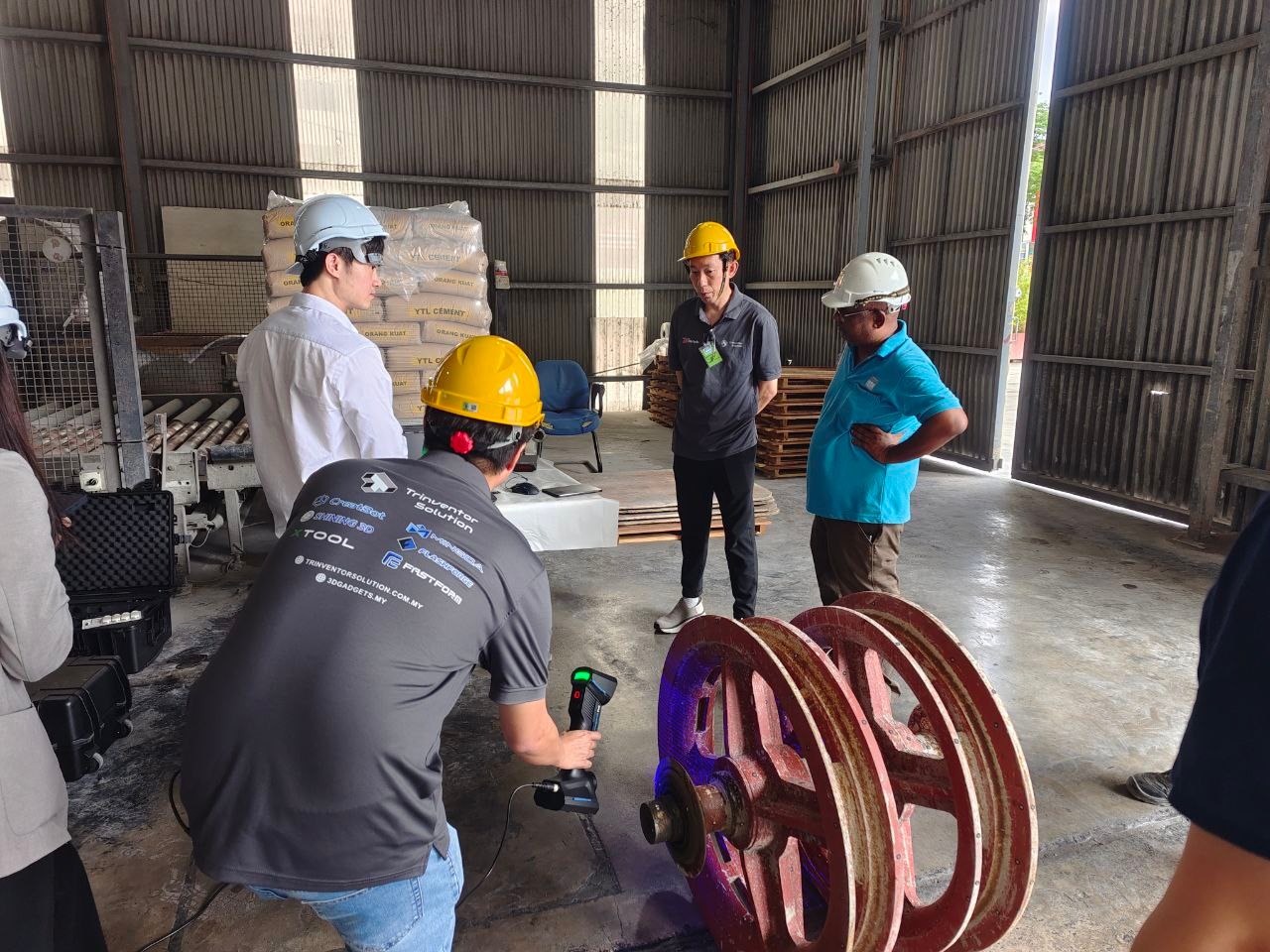 Large cast pulley wheel being 3D scanned on site in a Malaysian industrial warehouse