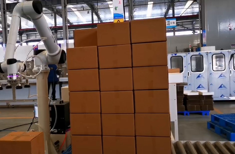 Palletizing robot arm placing cartons on a stack of boxes in a Malaysian warehouse