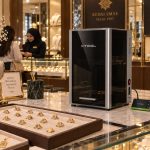 The xTool F2 Ultra on a jewellery shop counter beside trays of gold rings and custom engraving signboards