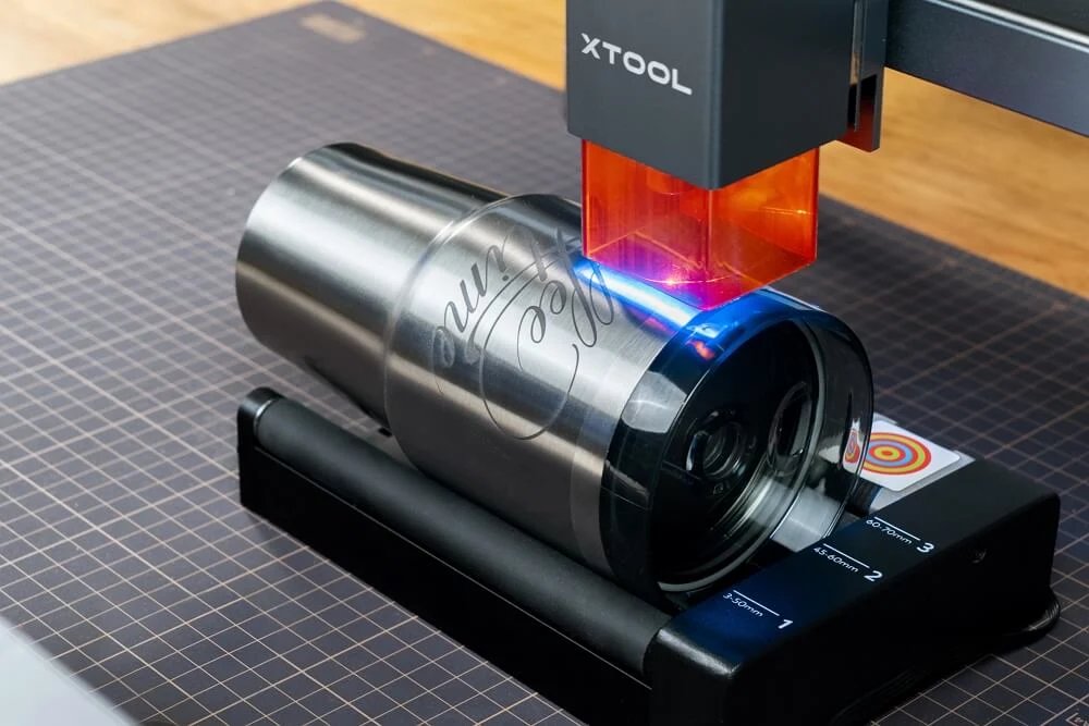 xTool laser engraving a stainless steel tumbler held in a rotary attachment