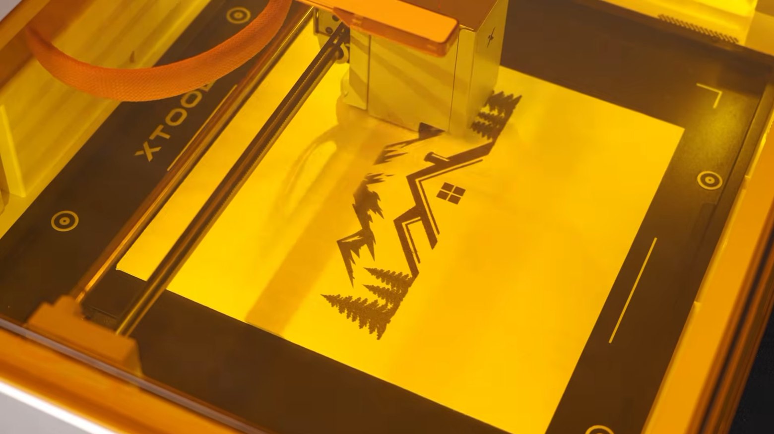 Di dalam mesin laser xTool, kepala laser sedang mengukir corak pokok pain pada permukaan kayu